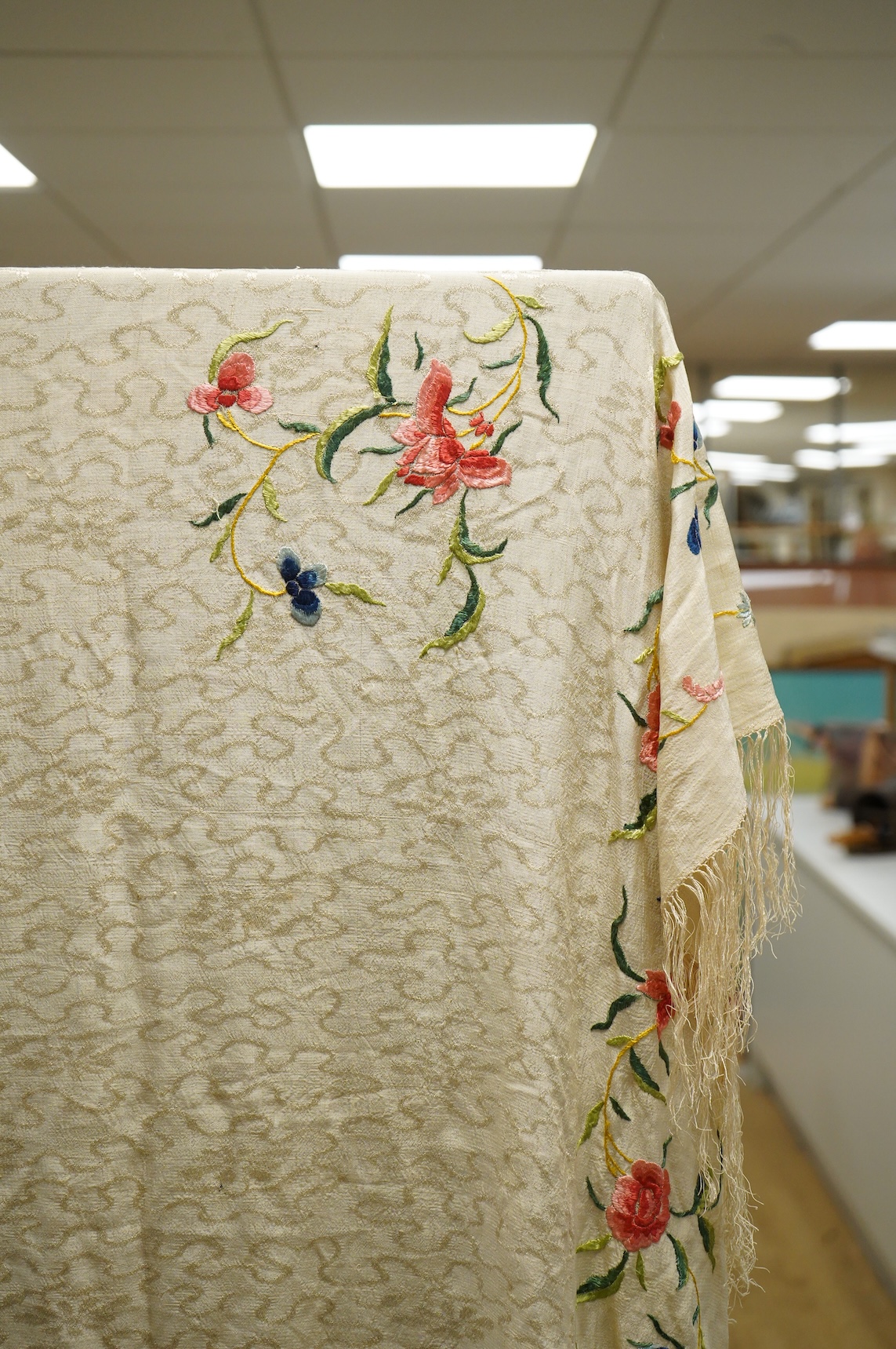 An early Chinese 20th century cream silk damask shawl with a polychrome floral silk embroidered border and a silk fringe, 150cm x 150cm, together with a smaller shawl/scarf, the corner cream on cream embroidered and edgi